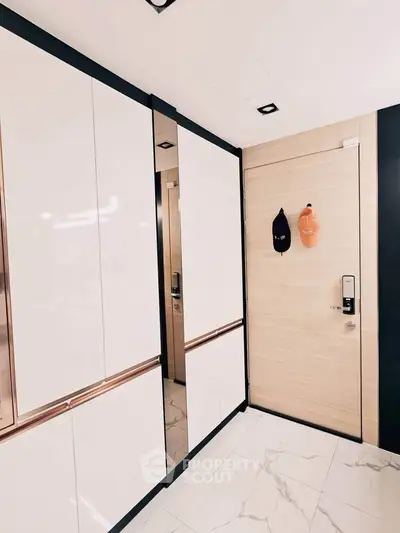 Modern entryway with sleek storage cabinets and digital door lock in a stylish apartment.