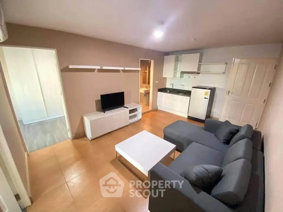 Modern living room with sleek furniture and compact kitchen in open layout apartment.