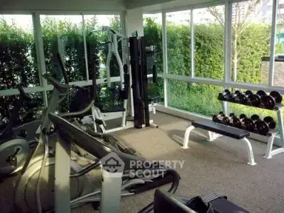 Modern gym with state-of-the-art equipment and lush garden views, perfect for fitness enthusiasts.