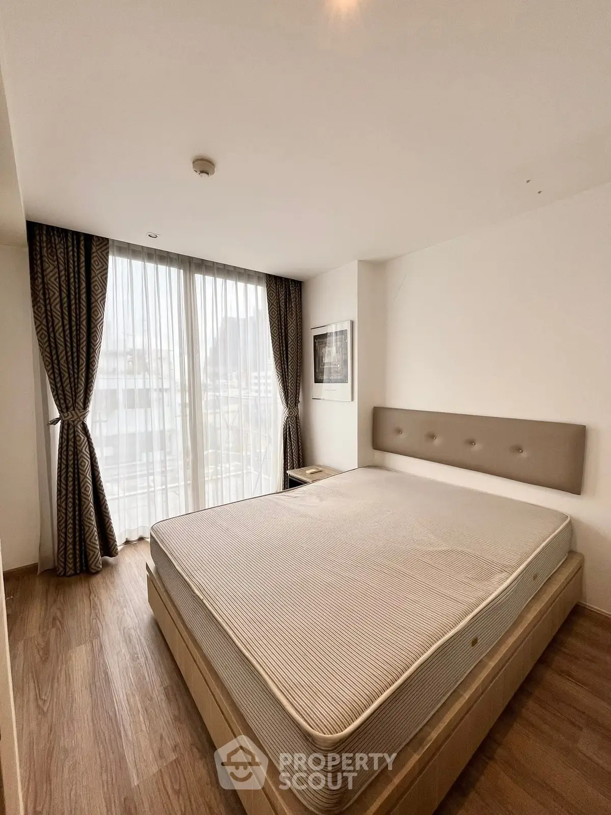 Modern bedroom with large window and stylish curtains in a bright apartment.