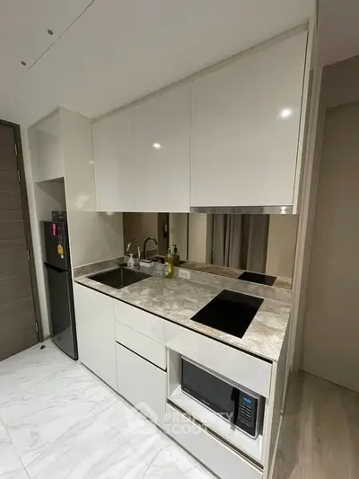 Modern kitchen with sleek white cabinets and marble countertop, featuring built-in appliances and minimalist design.