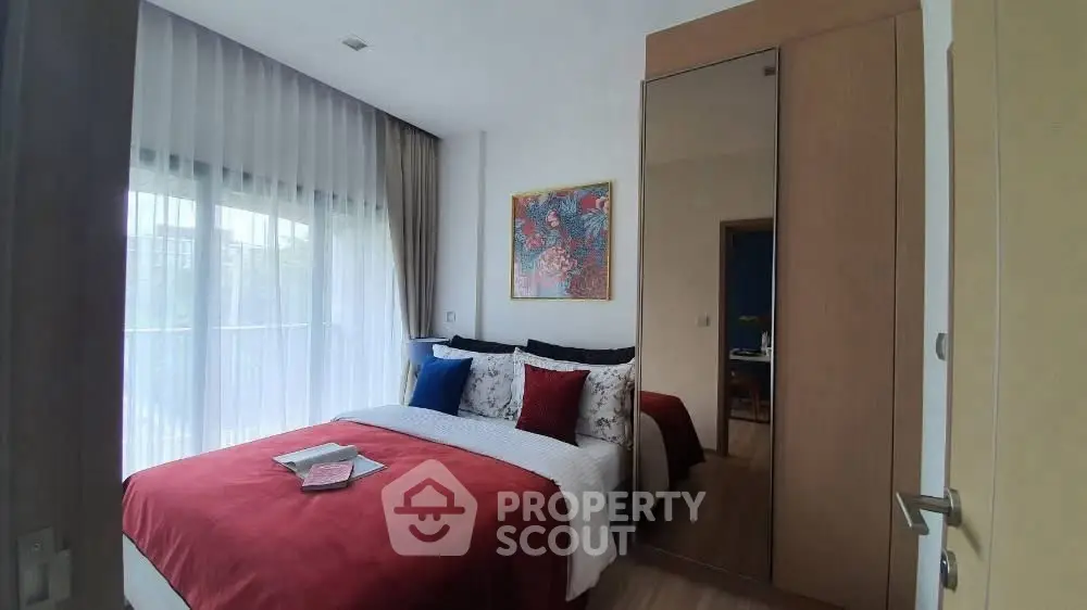 Cozy bedroom with vibrant decor and large window for natural light.