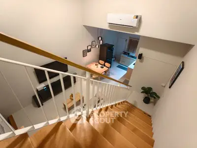 Modern duplex interior with stylish staircase and open living area, featuring sleek furniture and contemporary decor.