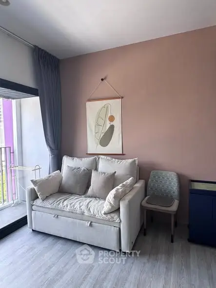 Cozy living room with modern decor and balcony access, featuring a stylish sofa and elegant wall art.