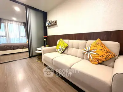 Modern living room with cozy sofa and vibrant cushions, adjacent to a stylish bedroom with natural light.