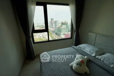 Cozy bedroom with stunning city view from large window, featuring modern decor and plush bedding.
