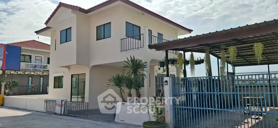 Charming two-story house with red roof and gated driveway in a sunny neighborhood.