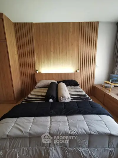 Modern bedroom with wooden paneling and cozy bedding in stylish apartment.