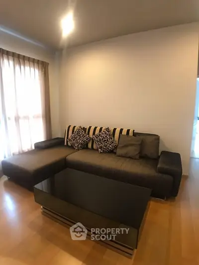 Modern living room with stylish sofa and glass coffee table, featuring elegant decor and natural light.
