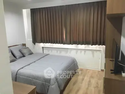 Cozy bedroom with modern decor and large window, perfect for relaxation.