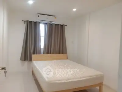 Spacious bedroom with natural light and modern air conditioning unit.