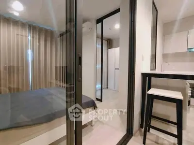 Modern apartment interior with bedroom and kitchen, featuring sleek design and neutral tones.