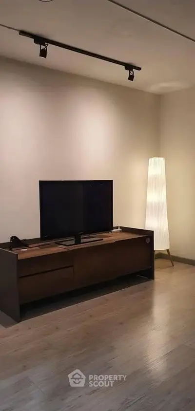 Modern living room with sleek TV stand and stylish floor lamp, perfect for cozy evenings.