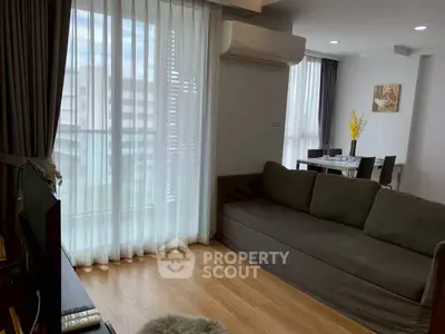 Modern living room with large windows and sleek furniture in a high-rise apartment.