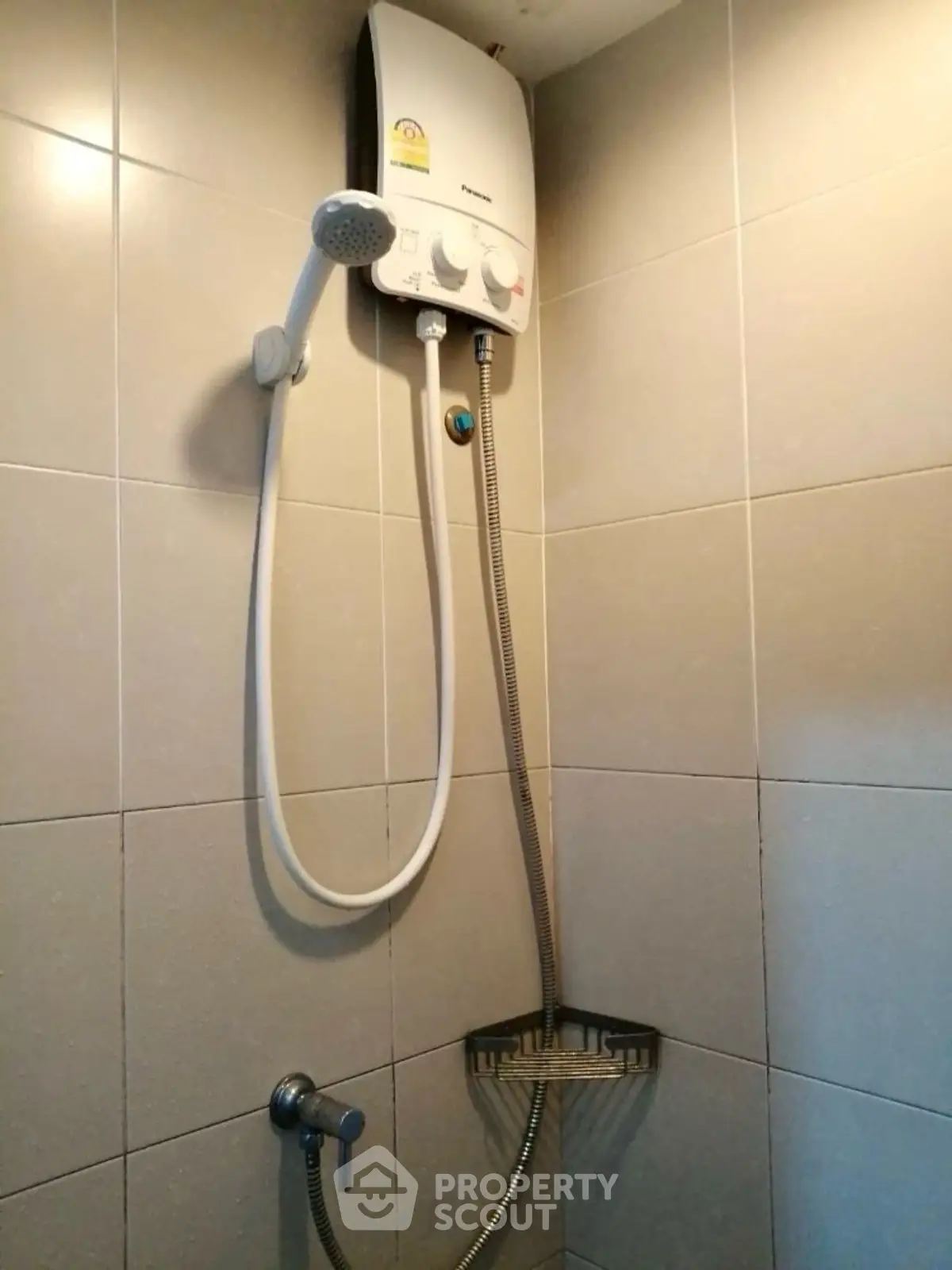 Compact bathroom shower area with modern water heater installation.