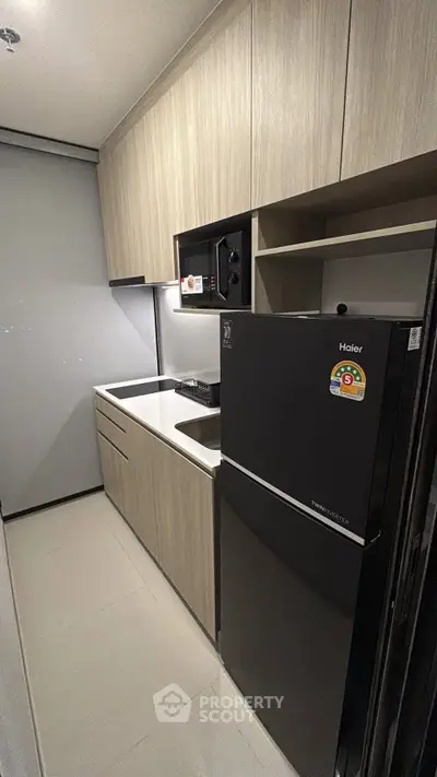 Modern kitchen with sleek cabinetry and compact fridge in a stylish apartment.
