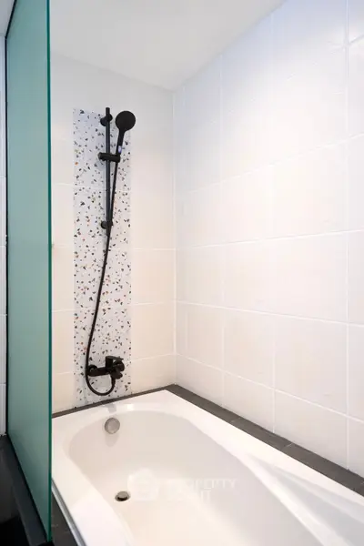 Modern bathroom with sleek bathtub and stylish showerhead in a minimalist design.