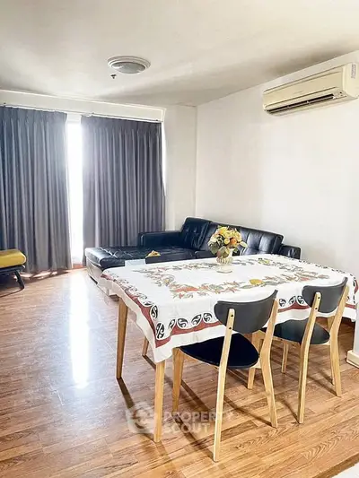 Spacious living room with wooden flooring, modern furniture, and natural light.