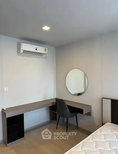 Modern bedroom with sleek desk, chair, and wall-mounted air conditioner.