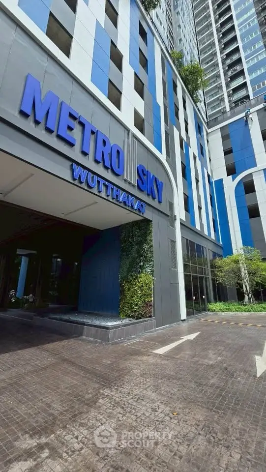 Modern high-rise building entrance with sleek design and blue accents at Metro Sky Wutthakat.