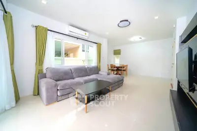 Spacious modern living room with large sofa and dining area, perfect for family gatherings.