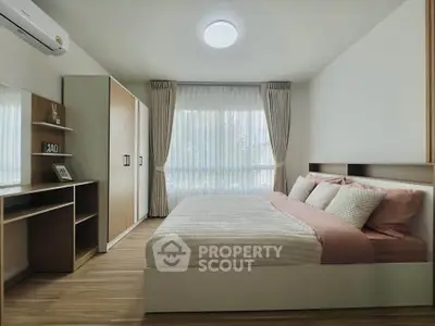 Spacious bedroom with modern furnishings and large window for natural light.