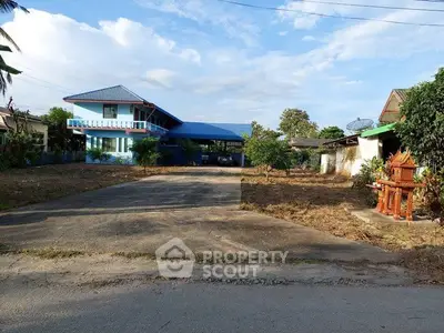 Charming blue two-story house with spacious driveway and lush greenery, perfect for serene living.