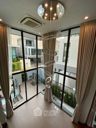 Luxurious modern living room with floor-to-ceiling windows and elegant chandelier.