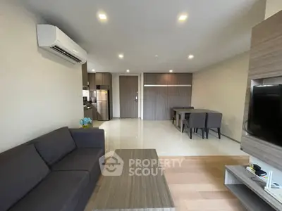 Modern living room with sleek furniture and open layout, featuring a cozy sofa and dining area.