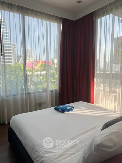 Spacious bedroom with large windows offering a stunning city view, perfect for urban living.