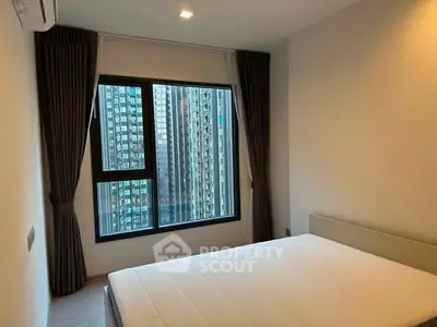 Modern bedroom with large window offering city view in high-rise apartment.
