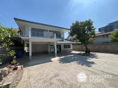 Spacious two-story house with large driveway and lush tree in sunny suburban setting.