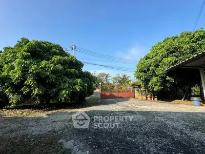 Spacious garden with lush greenery and gated entrance, perfect for privacy and relaxation.