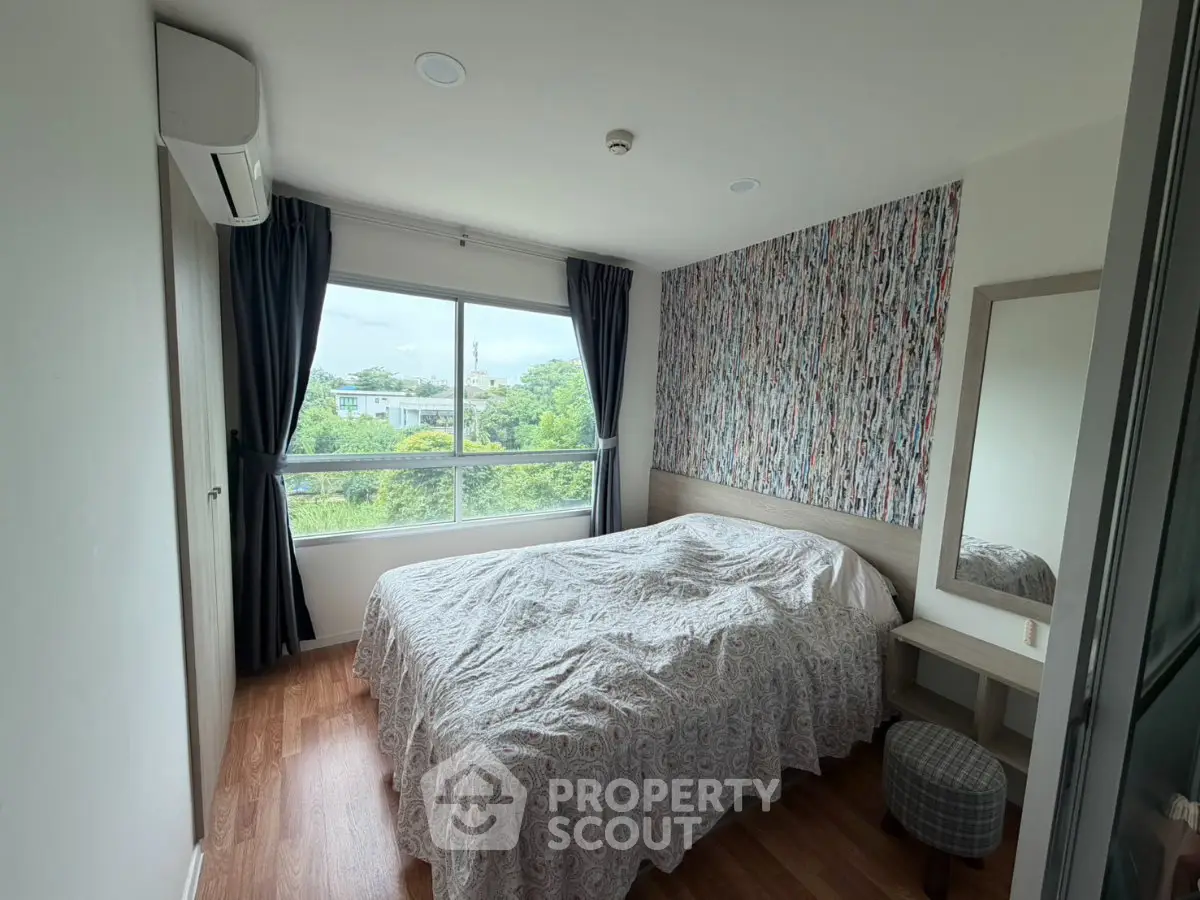 Cozy bedroom with large window and scenic view, featuring modern decor and air conditioning.