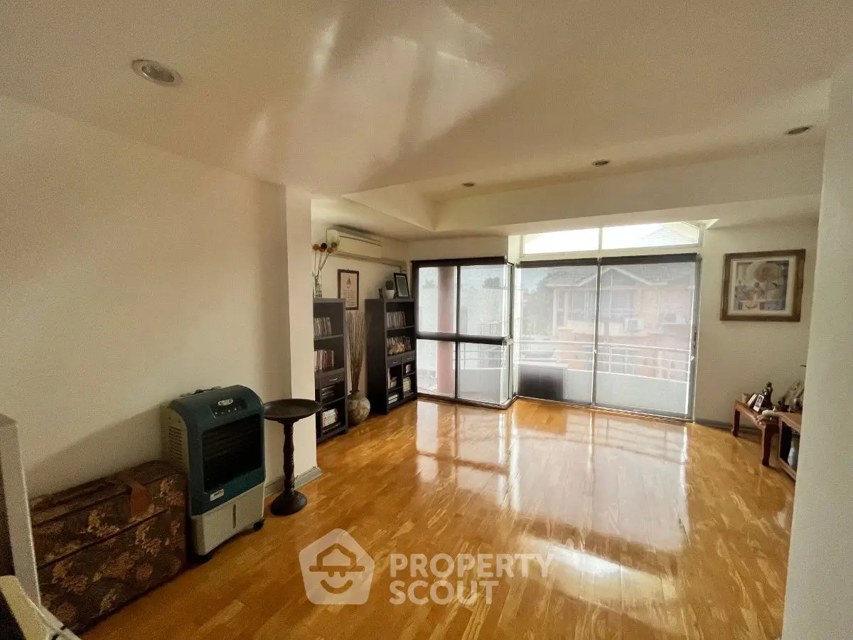 Spacious living room with wooden flooring and large windows for natural light.