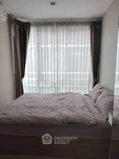 Cozy bedroom with large window and elegant curtains, perfect for natural light lovers.