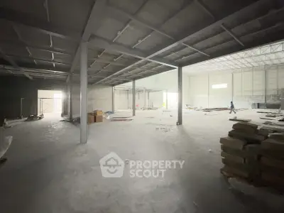 Spacious industrial warehouse interior with high ceilings and ample natural light.