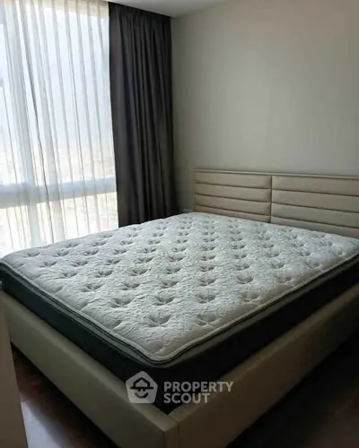 Spacious bedroom with large window and modern bed in a stylish apartment.