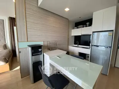 Modern kitchen with sleek design, featuring a glass dining table, stainless steel fridge, and compact layout.
