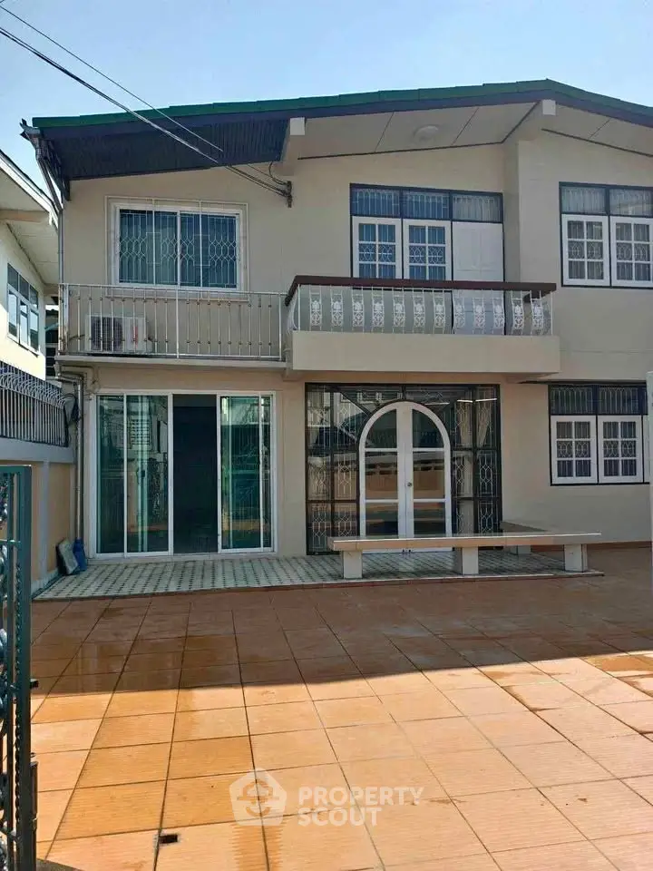 Charming two-story house with spacious tiled patio and balcony, perfect for family living.