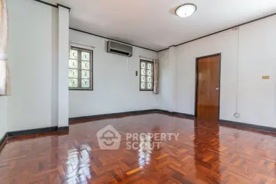 Spacious empty room with polished wooden floors and natural light.