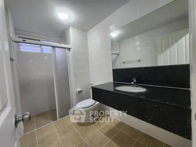 Modern bathroom with sleek black countertop and spacious shower area.