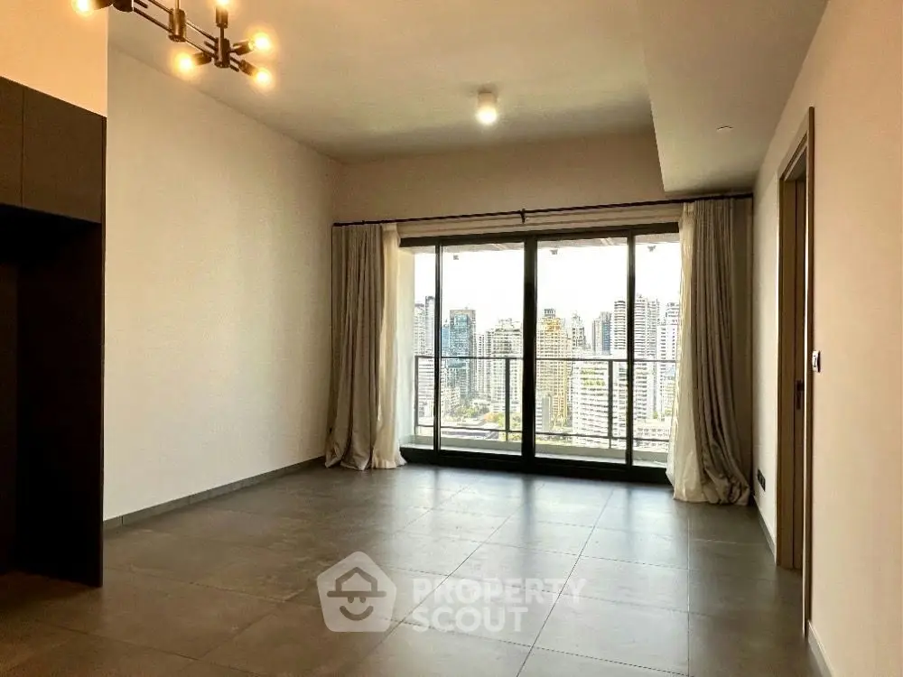 Spacious living room with large windows offering stunning city views in modern apartment.