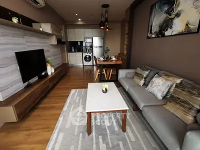 Modern living room with stylish decor and open kitchen layout, featuring a cozy sofa and elegant dining area.