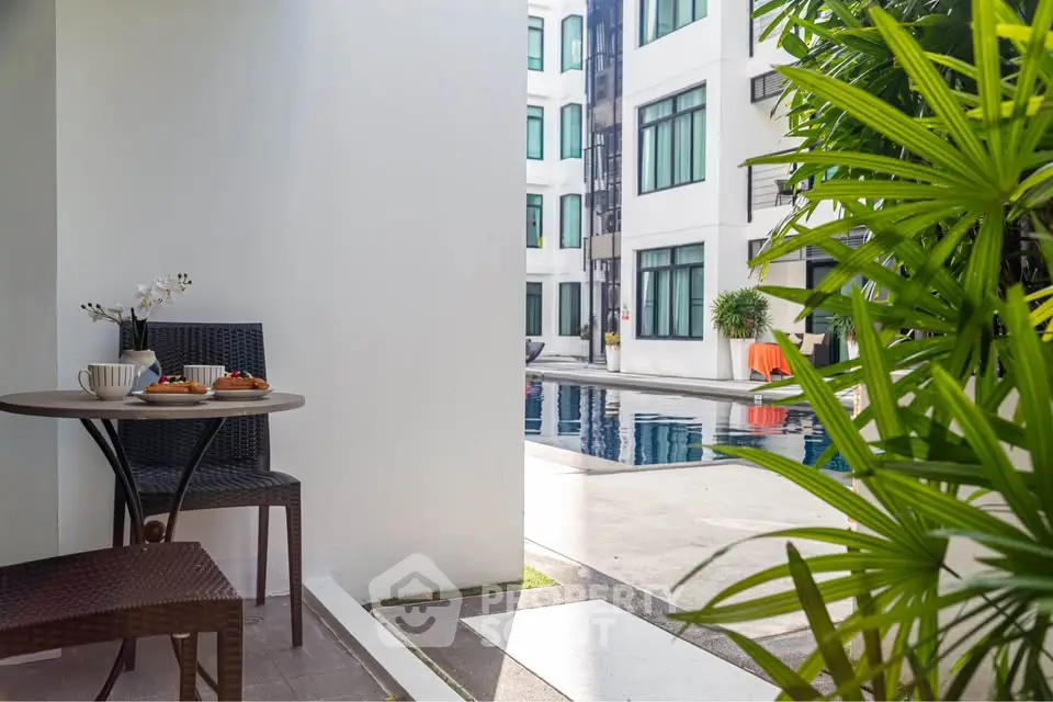 Charming poolside view from a cozy balcony with breakfast setup, perfect for relaxation.