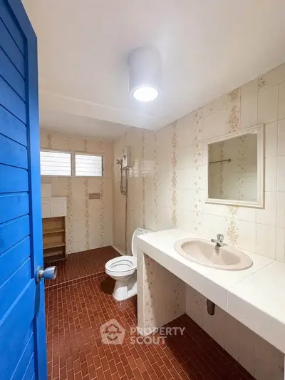 Charming bathroom with vintage tiles and modern fixtures, featuring a bright blue door and ample natural light.