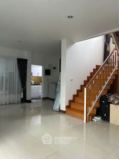 Spacious modern living area with staircase and kitchen view