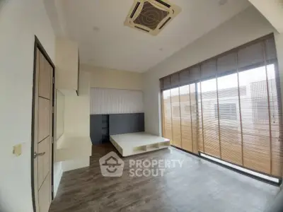Spacious modern bedroom with wooden flooring and large windows