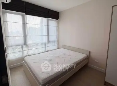 Modern bedroom with large windows and minimalist design in urban apartment.