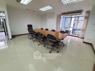 Spacious office meeting room with large table and modern chairs, ideal for corporate gatherings.